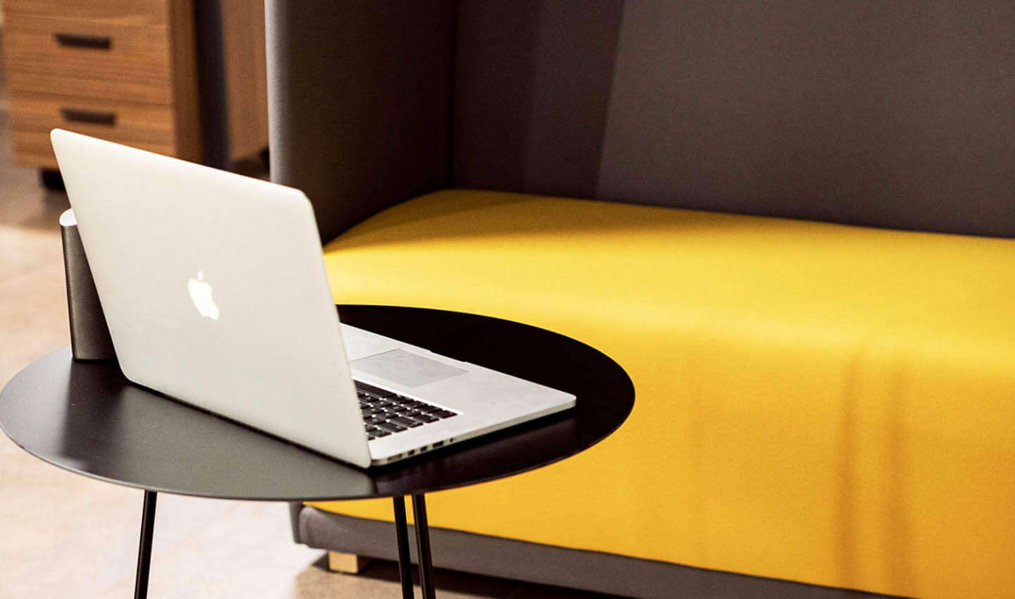 foto di un divano, tavolino e MacBook in un ufficio arredato creasystem